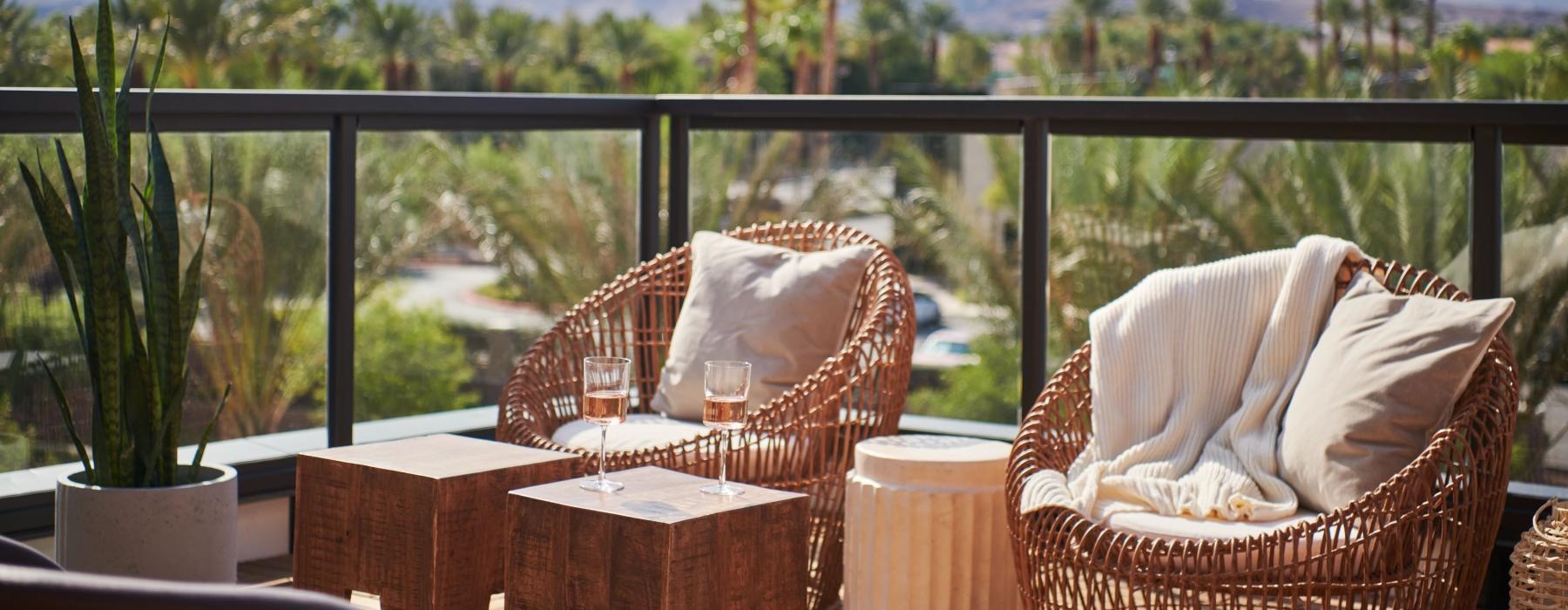 a deck with chairs and a table with a view of trees and mountains