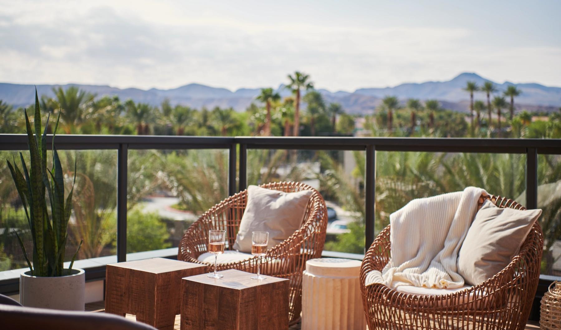 a deck with chairs and a table with a view of trees and mountains